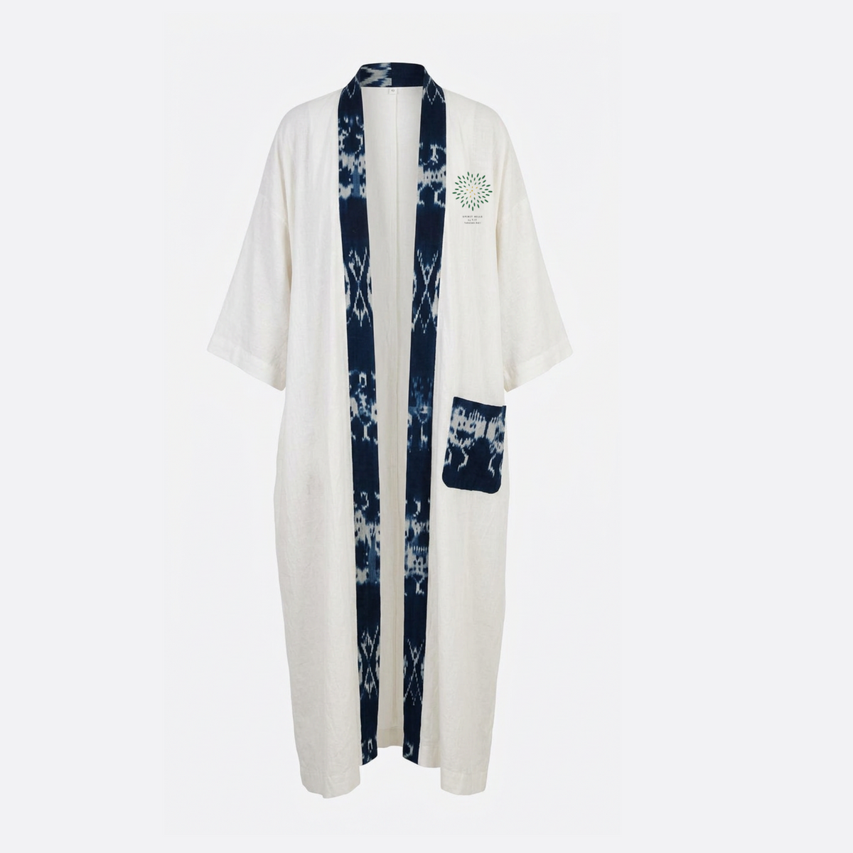 An off-white cotton robe with a dark indigo blue shibori tie-dye pattern running down the center front and along a vertical chest pocket. The left chest features a small green and white circular floral emblem.